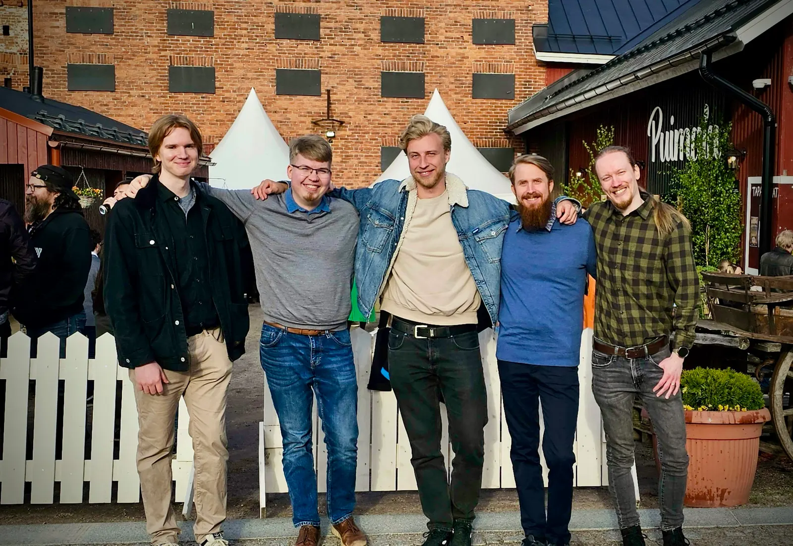 Five Visma players arm in arm outside a red-brick building.